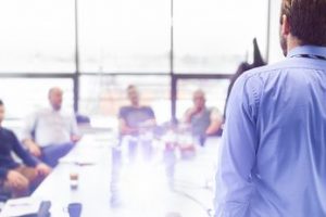 Business man making a presentation at office. Business executive delivering a presentation to his colleagues during meeting or in-house business training, explaining business plans to his employees.